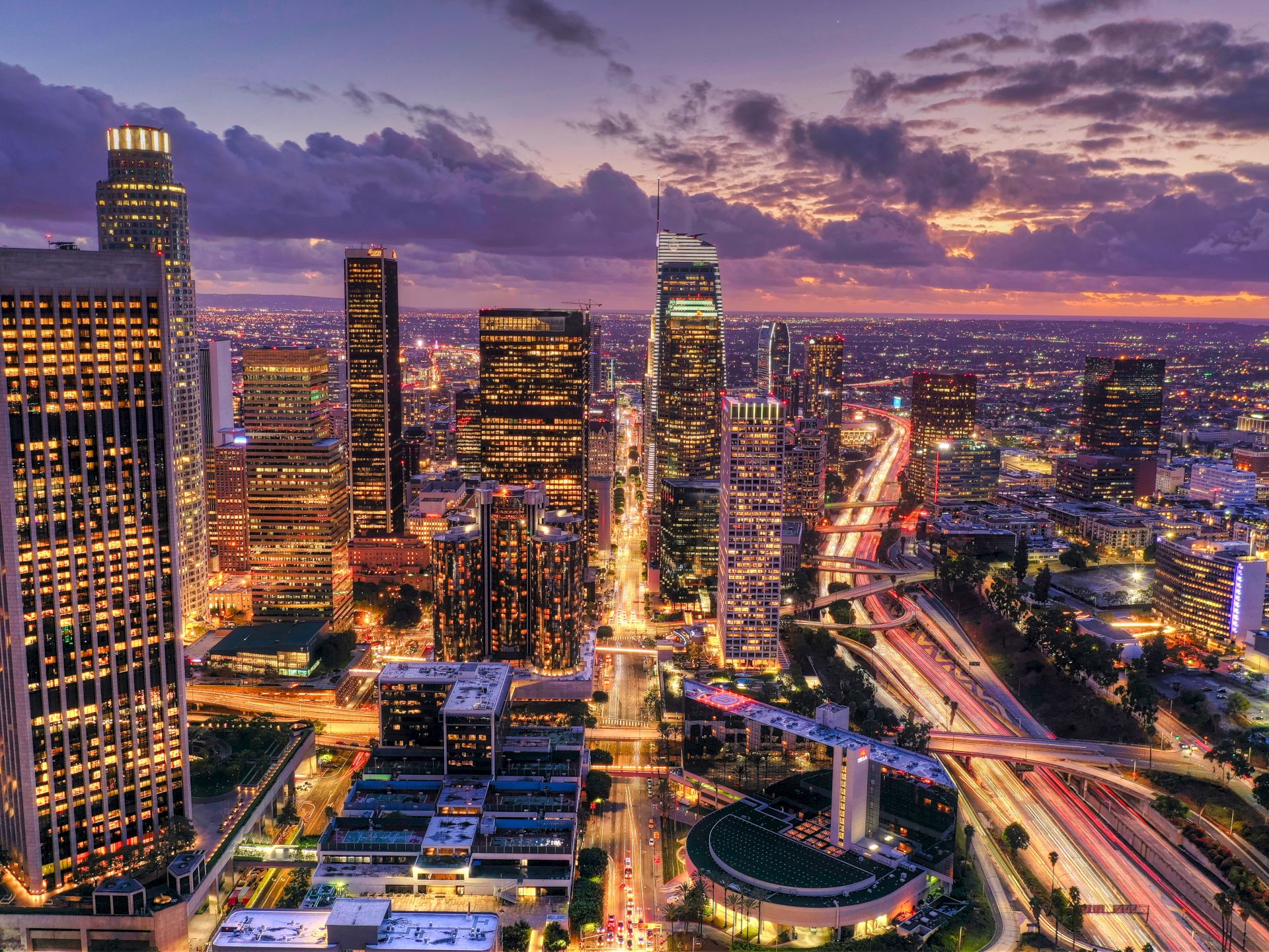 A cityscape at sunset with skyscrapers and a highway