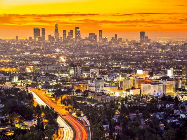A cityscape at sunset with a highway in the foreground