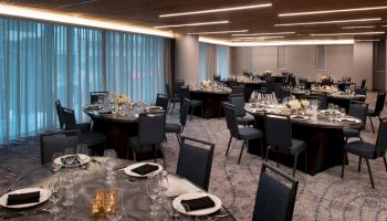 The image shows an elegant banquet hall set up with round tables, chairs, and place settings, ready for a formal event or dinner.